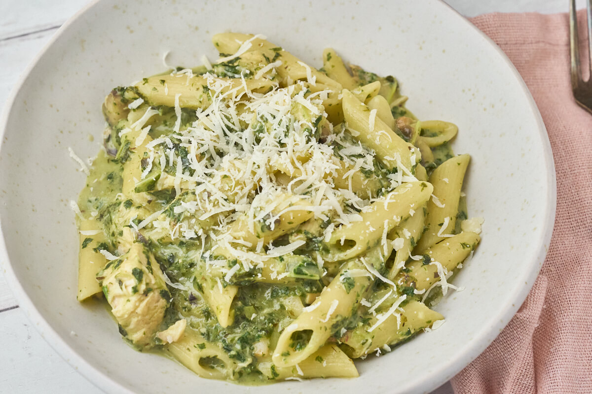 tallerken med one pot pasta med kylling og grønkål toppet med revet parmesan.