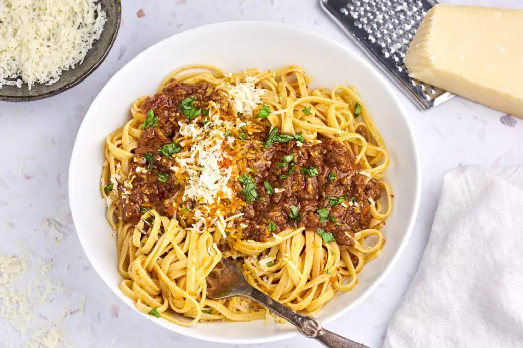 original spaghetti bolognese serveret i hvid tallerken med linguine, bolognese, parmesan og basilikum