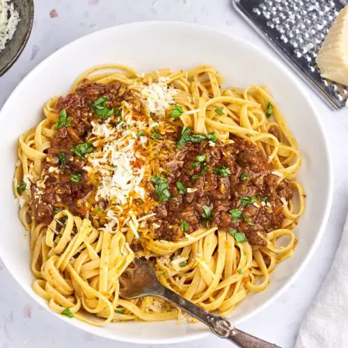 original spaghetti bolognese serveret i hvid tallerken med linguine, bolognese, parmesan og basilikum