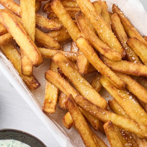 sprøde hjemmelavede pommes frites lavet i friture serveret med ketchup og ranch.