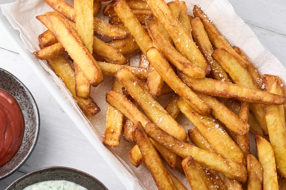 sprøde hjemmelavede pommes frites lavet i friture serveret med ketchup og ranch.