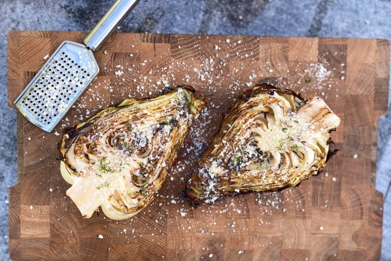 Grillet spidskål med parmesan på skærebræt.