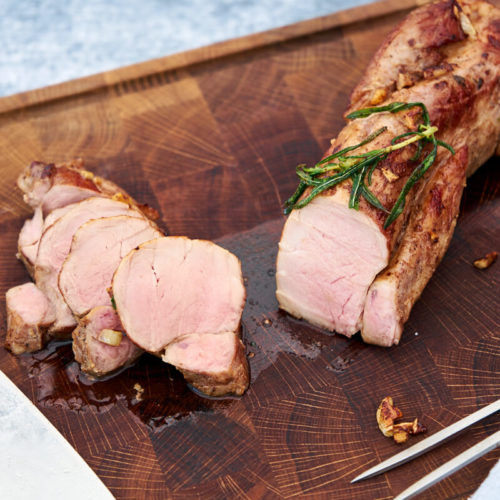 Saftig svinemørbrad sous vide skåret i skiver på skærebræt.