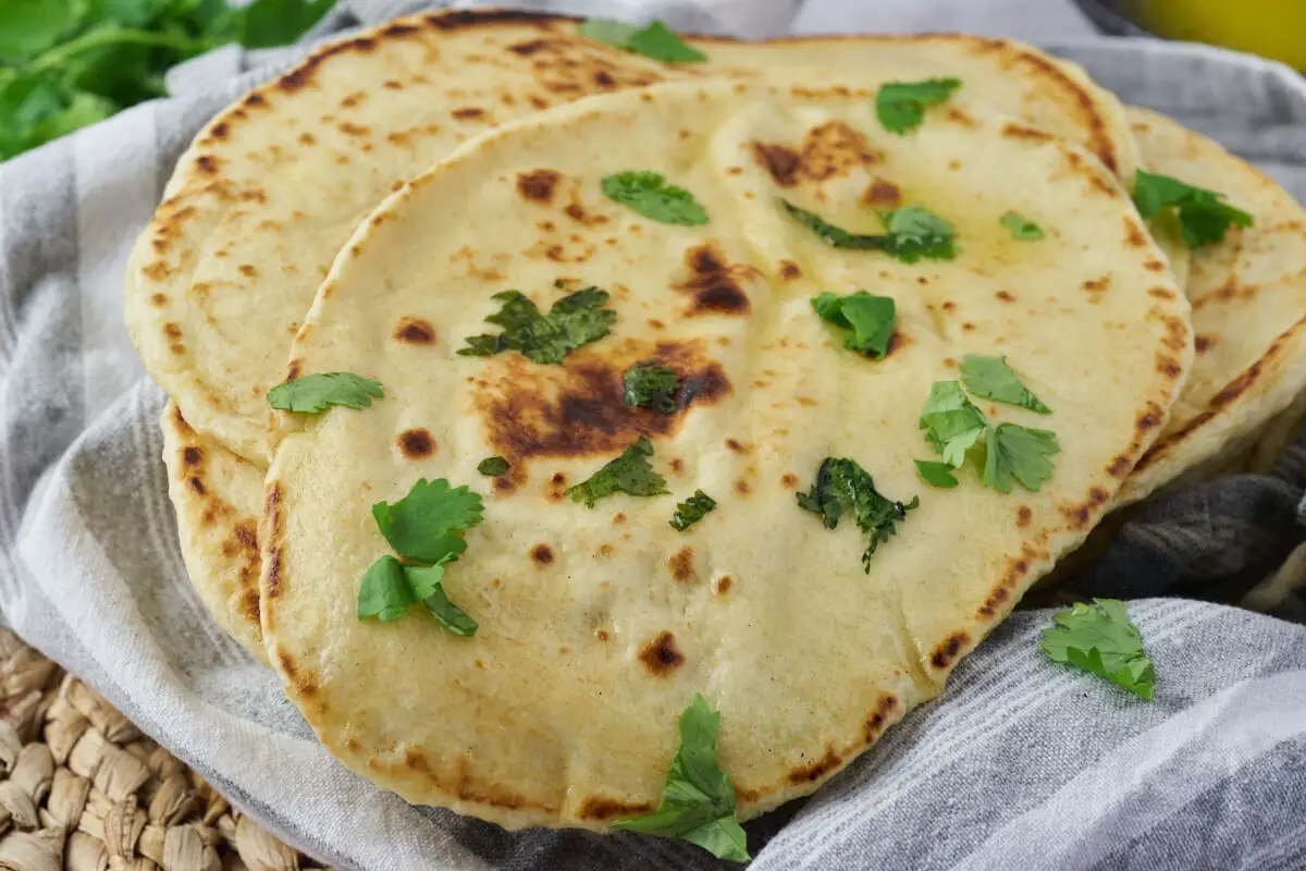 indiske naan brød med smør og koriander i viskestykke klar til servering