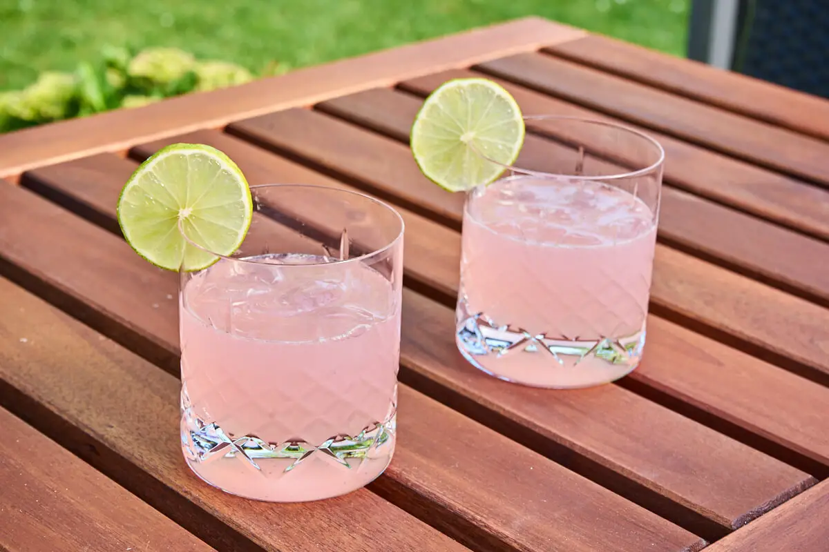 rabarber gin hass cocktail med gin og rabarbersirup samt limeskive på kanten af glasset