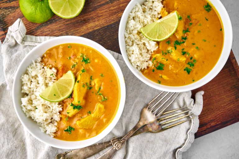 Indisk kylling i karry serveret med ris og lime.