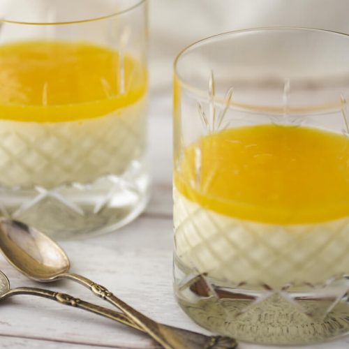 Panna cotta i glas med mango-gele på toppen og to skeer.
