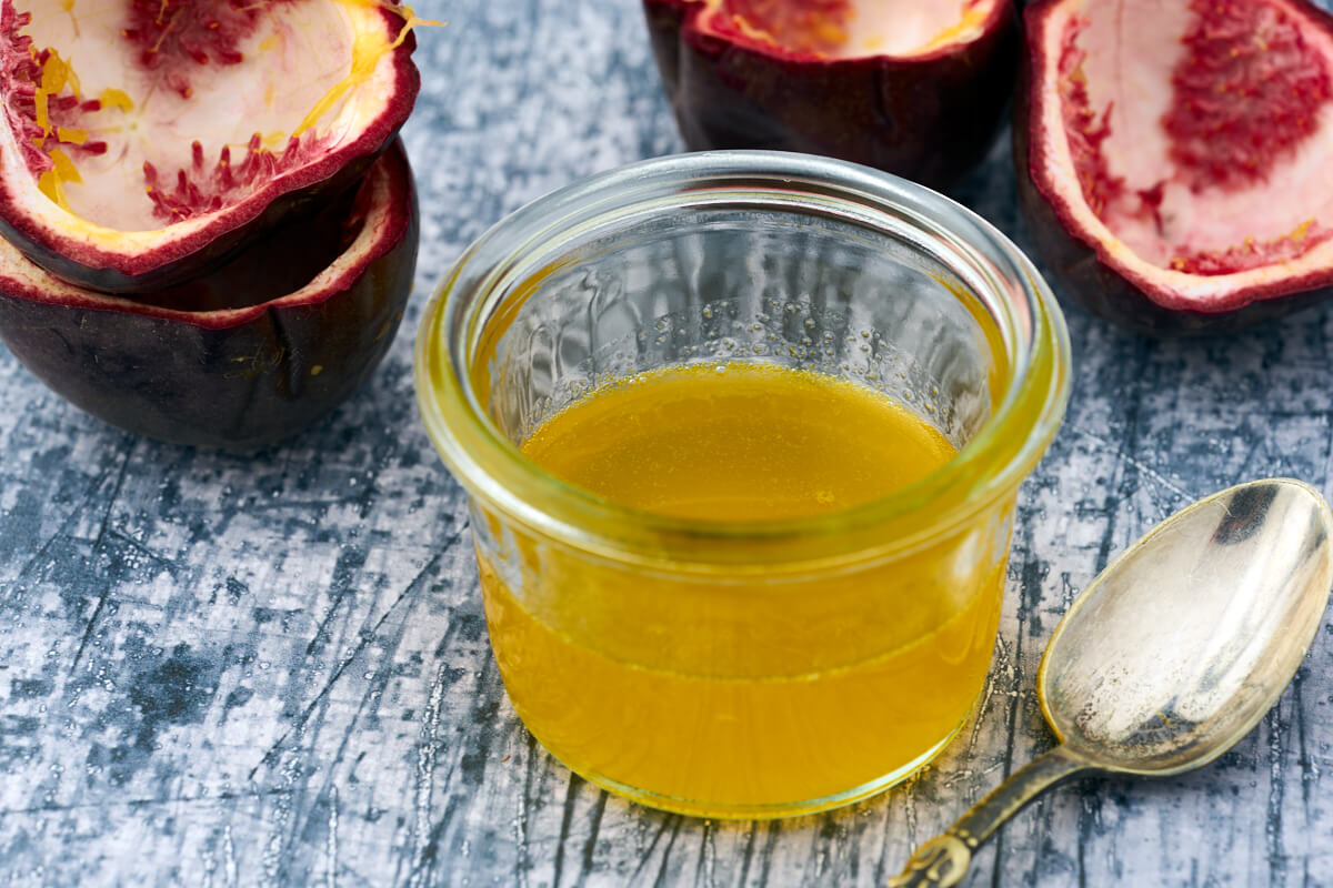 Passionsfrugtsirup i et lille glas med skaller fra passionsfrugten.