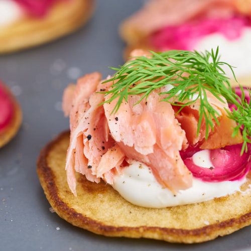 Blinis med varmrøget laks, rødløg, creme fraiche og dild