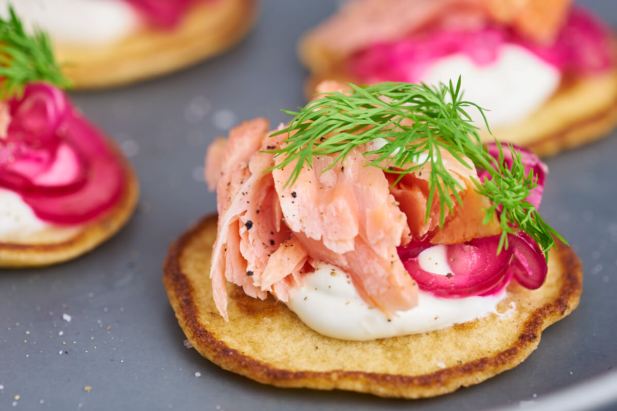 Blinis med varmrøget laks, rødløg, creme fraiche og dild