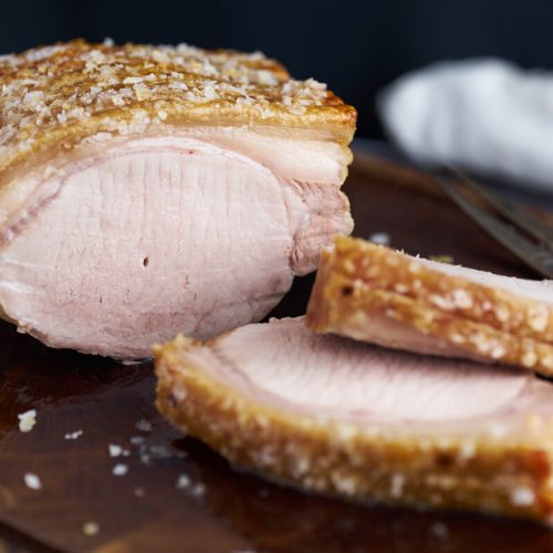 pork roast with crackling on chopping board with slices of pork roast