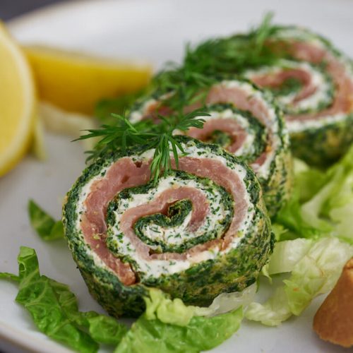 3 skiver spinatroulade på tallerken med salat, citron og flutes.