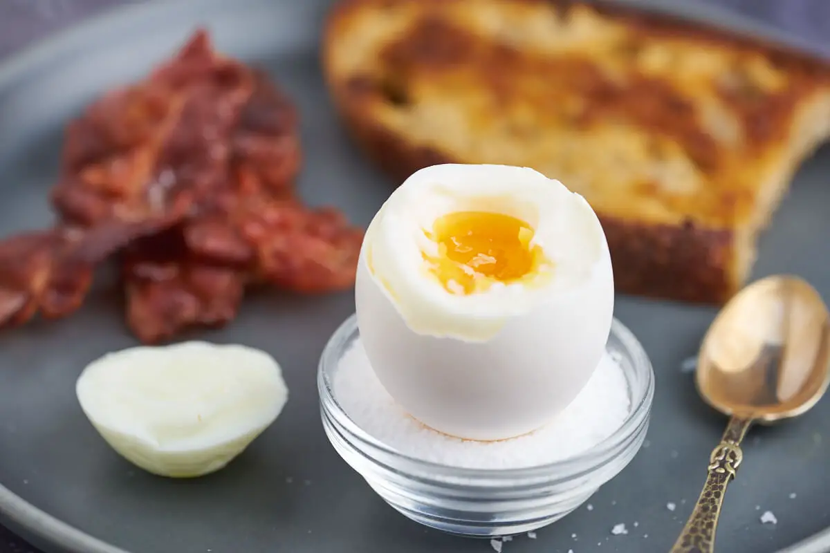 bløgkogt æg, bacon og ristet brød på morgenbordet, perfekt morgenmadstallerken