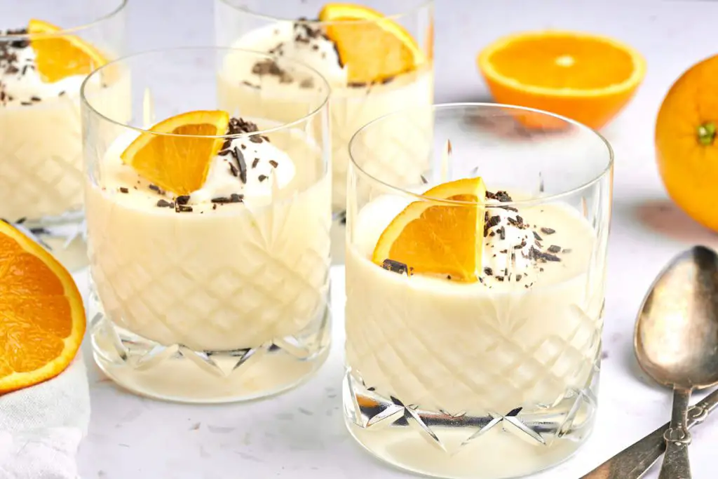 orange mousse in glass with whipped cream, orange slice and chocolate on top