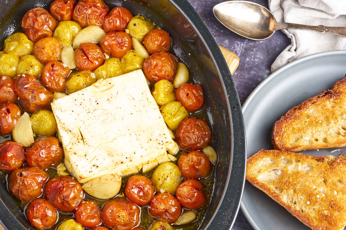 bagt feta med tomat serveret i fad med sprødt brød