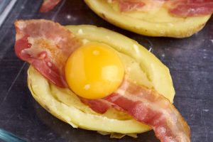 Dobbeltbagte kartofler med mos, bacon og æg i klar til at komme i ovnen.