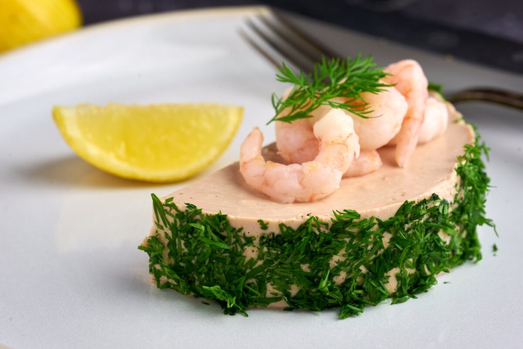 portionsanrettet tunmousse med husblas pyntet med rejer og dild.