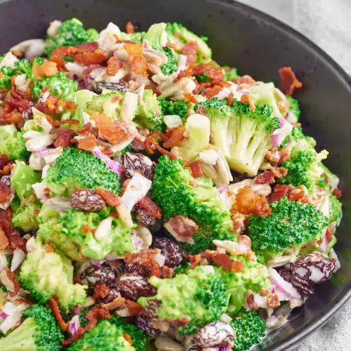 sort skål med broccolisalat med bacon, rødløg og rosiner