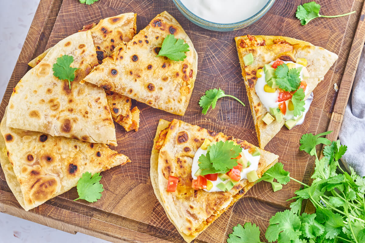 Quesadillas med kylling og cheddar serveret med creme fraiche, avocado, tomat og frisk koriander