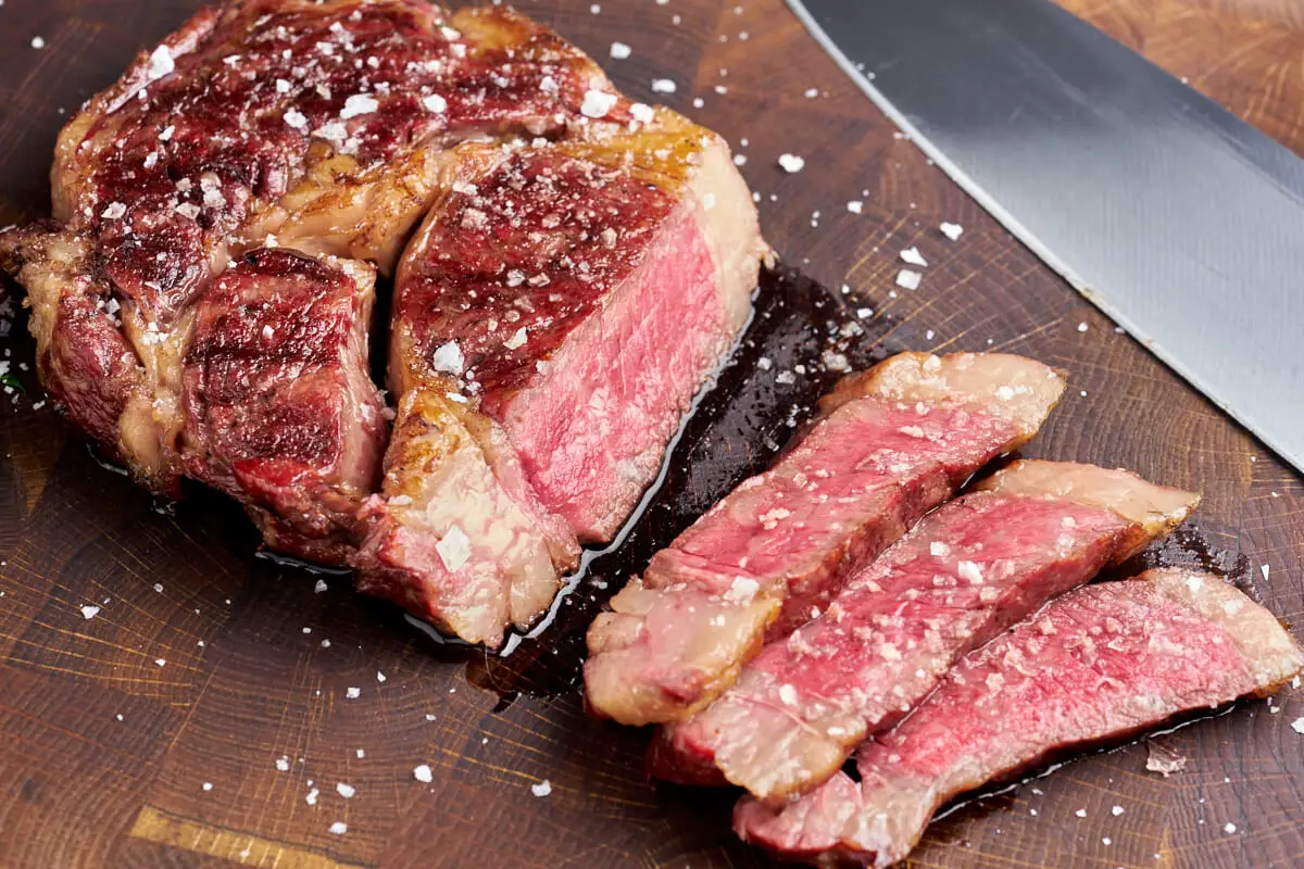 udskåret ribeye steak af wagyu med kniv ved siden af på skærebræt