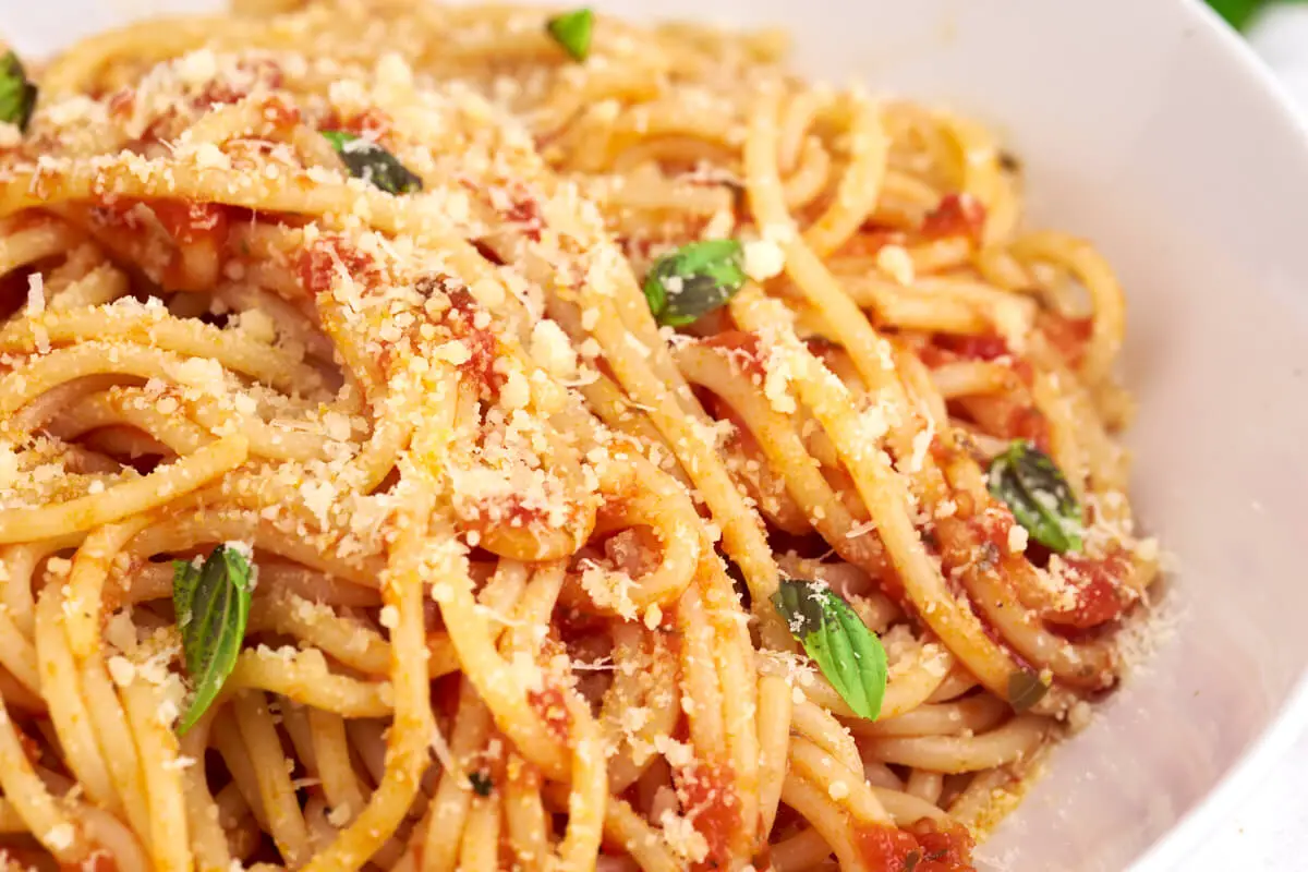 tallerken med pasta pomodoro med tomatsauce og parmesan på toppen