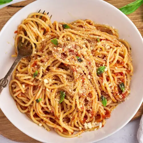pasta pomodoro eller spaghetti med tomatsovs i tallerken med basilikum og parmesan på toppen