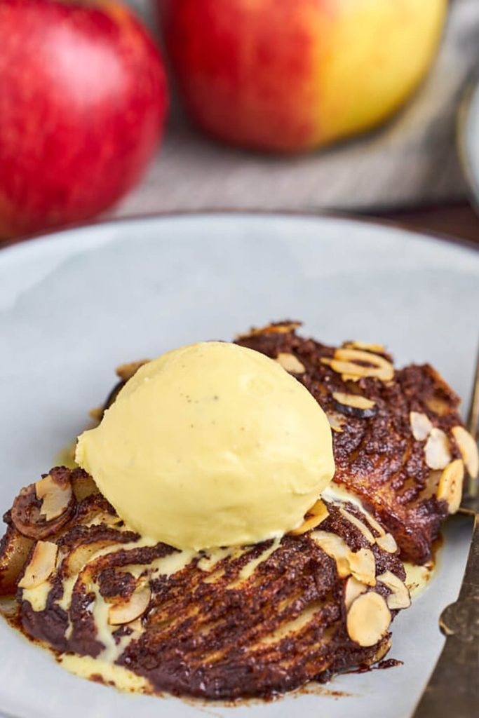 hasselback æbler med hjemmelavet vaniljeis på tallerken og æbler i baggrunden.