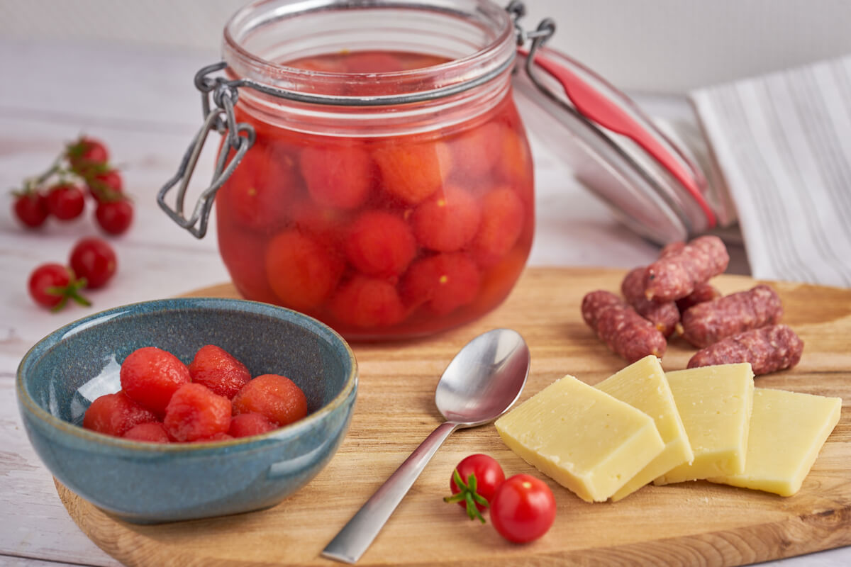 syltede cherrytomater i glas med syltelage og i skål serveret til tapas