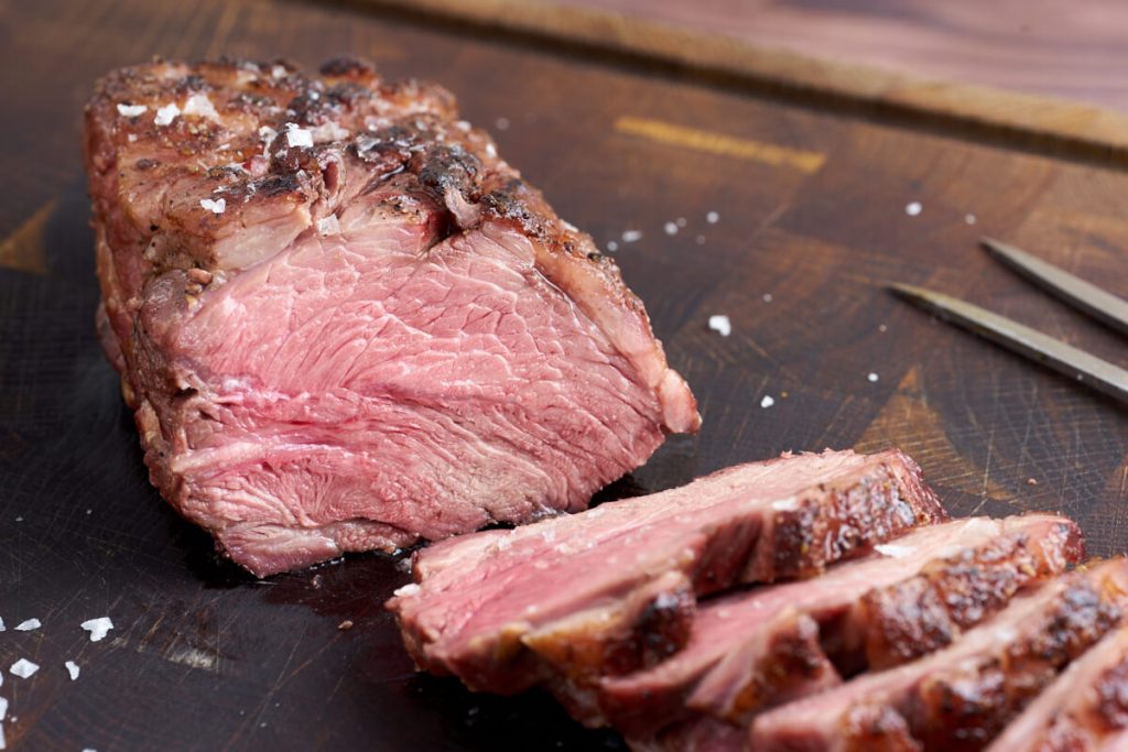 skiveskåret grillet lammeculotte på skærebræt.