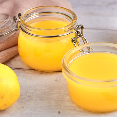 hjemmelavet lemon curd i glas med citroner ved siden af