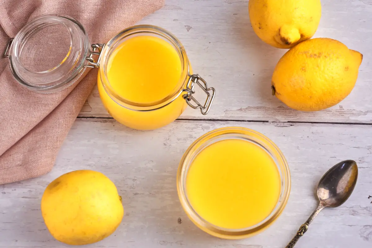 to glas med hjemmelavet lemon curd og citroner ved siden af