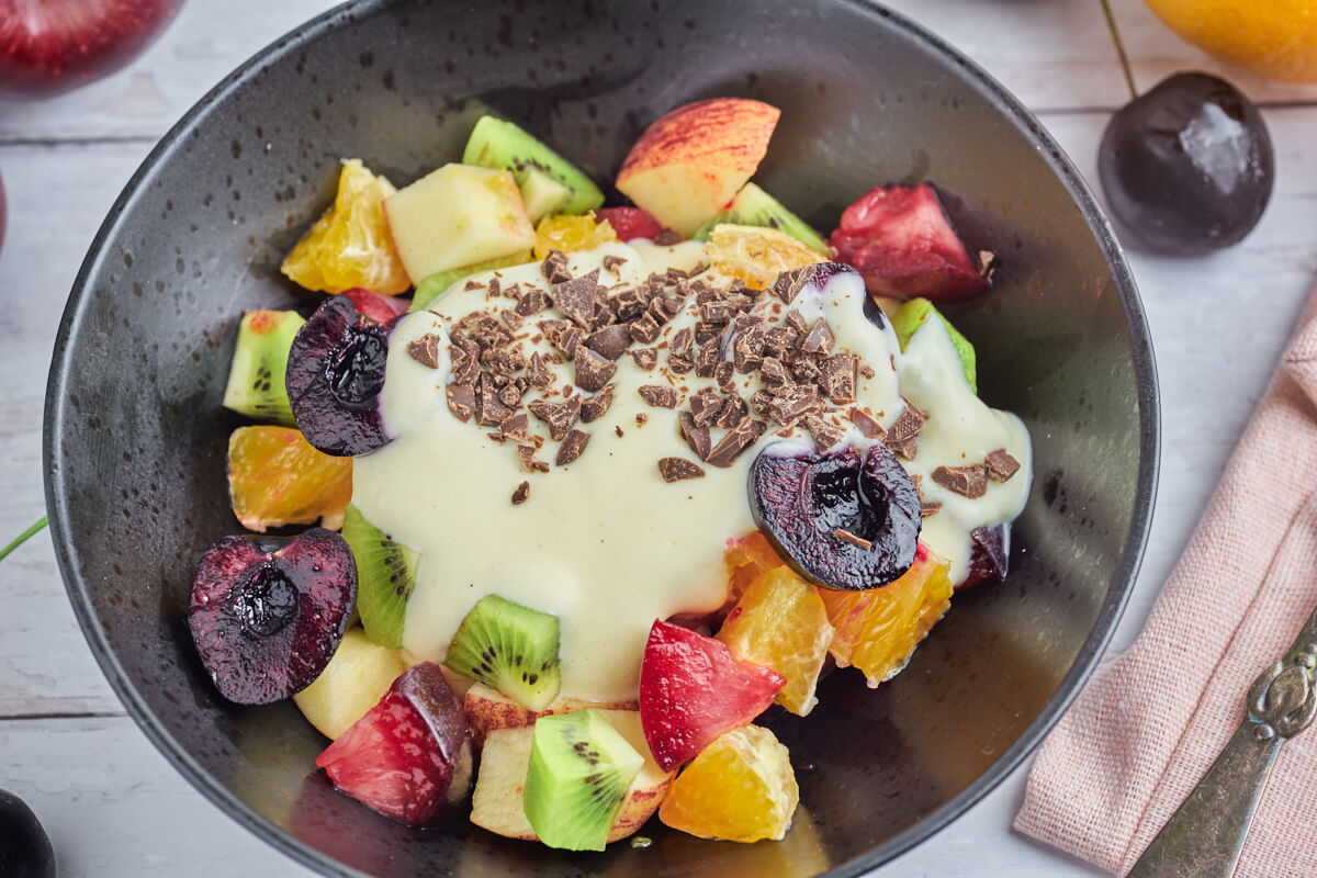 frugtsalat med råcreme og hakket mørk chokolade i sort skål