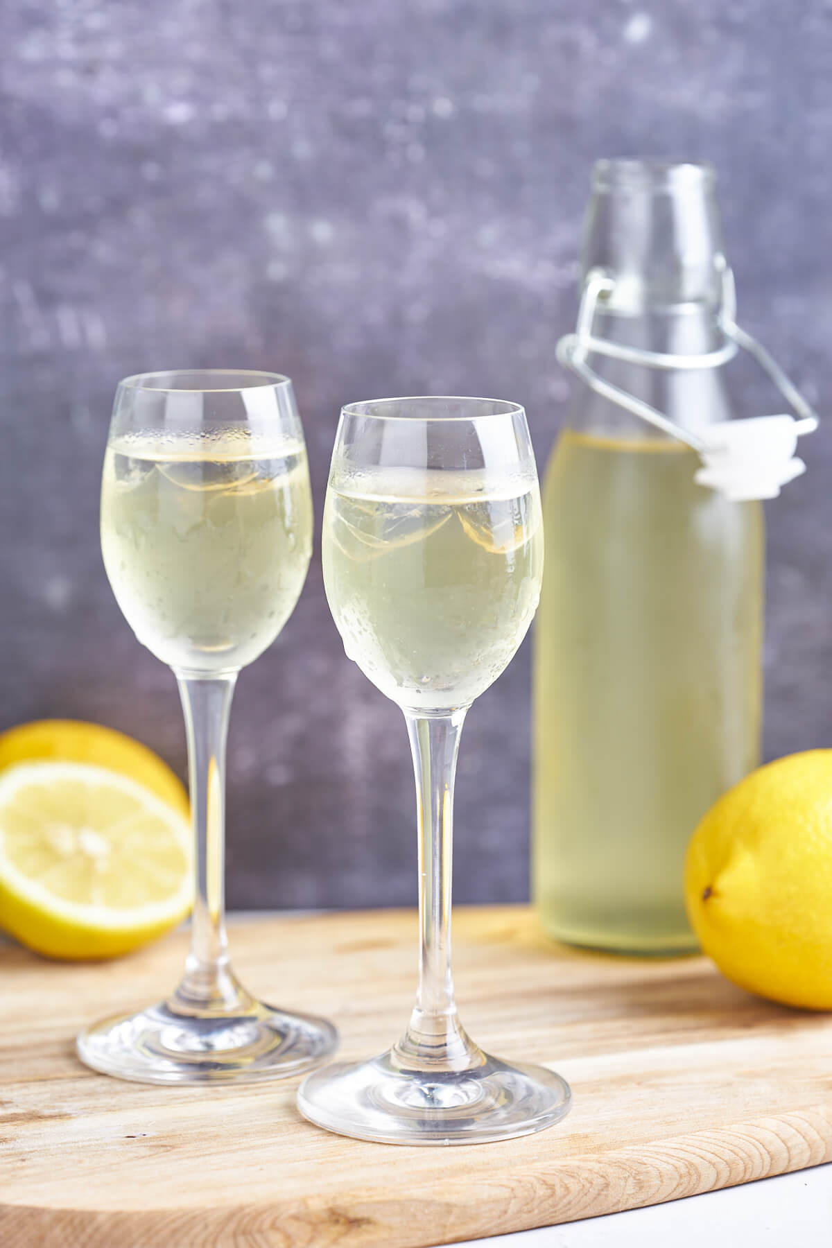 to glas med hjemmelavet limoncelle samt flaske og citroner bagved