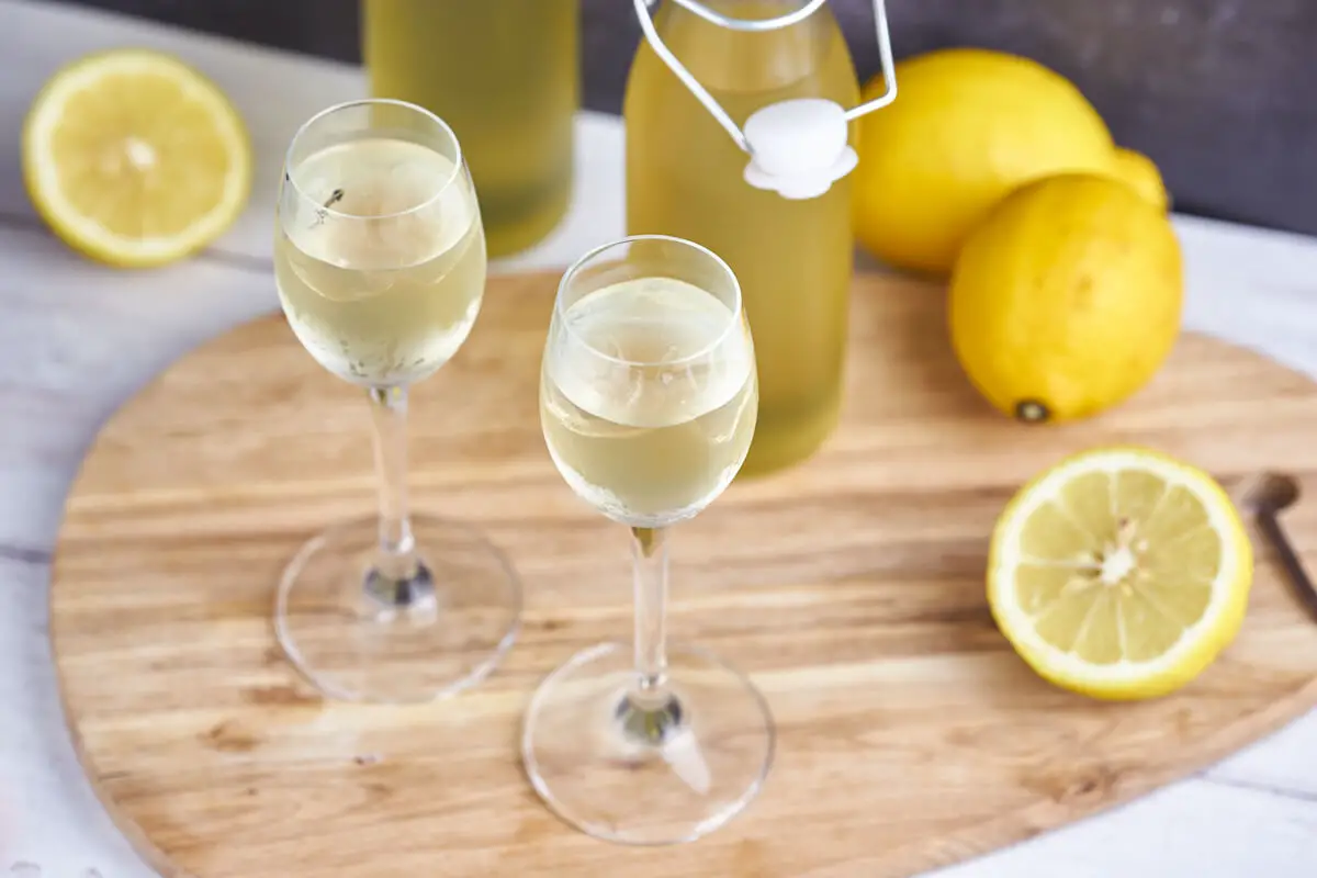 hjemmelavet limoncello i glas med flasker og citroner
