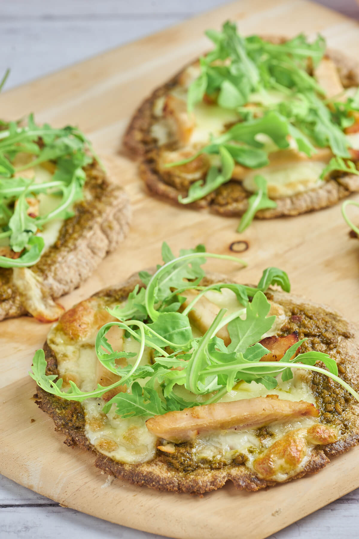 pita pizza med kylling og pesto serveret med rucola på toppen