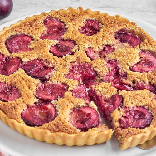 blommetærte med frangipane på tallerken med blommer bagved