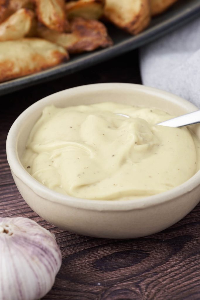 skål med aioli og sprøde kartofler i baggrunden.