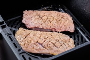 rå andebryster i airfryer klar til tilberedning.