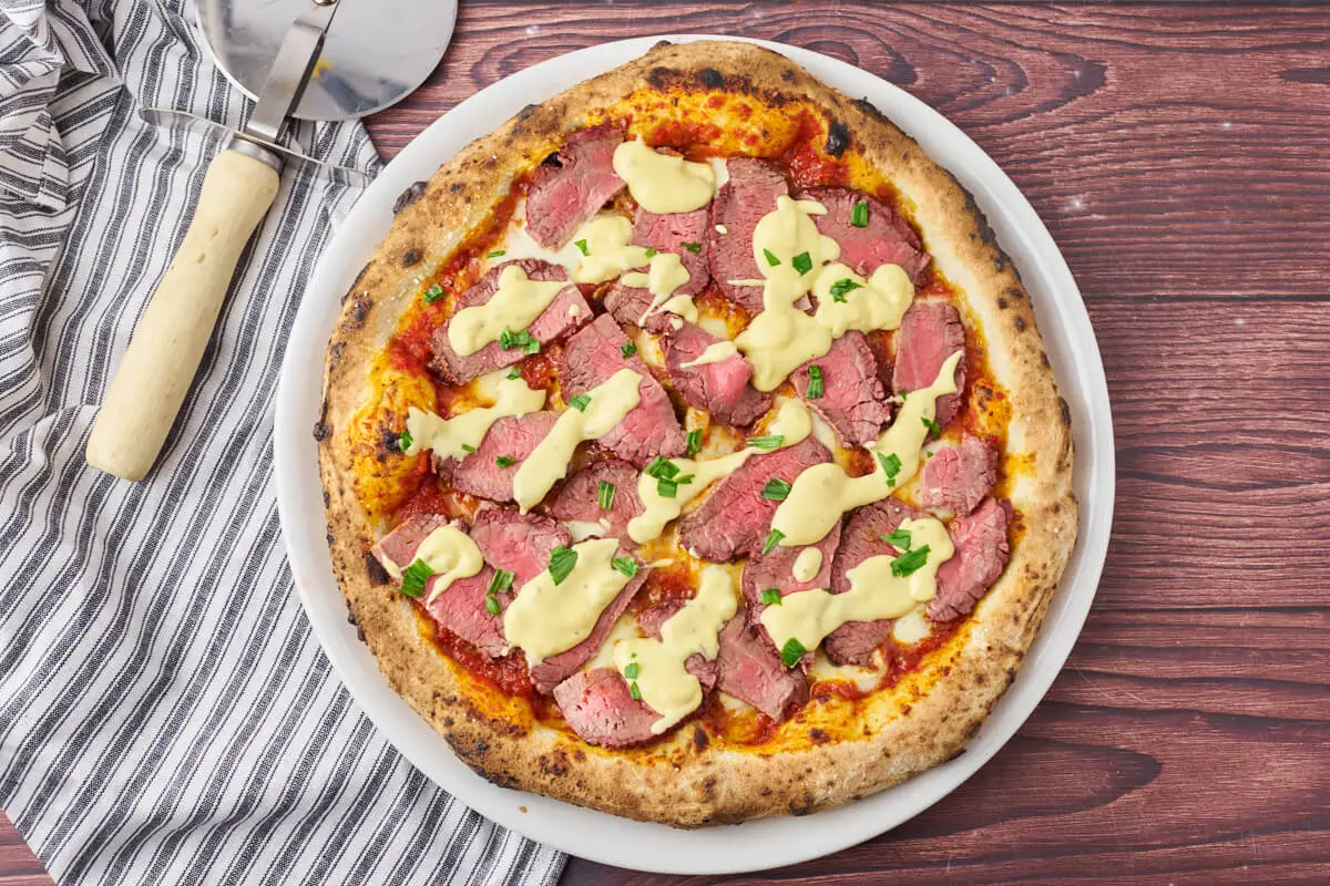 bøf bearnaise pizza på tallerken med pizzahjul