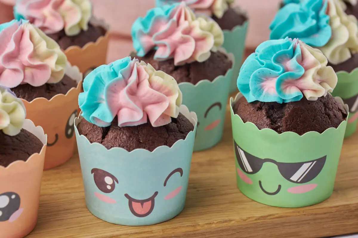 chokolade cupcakes med flerfarvet smørcreme i sjove muffinsforme med ansigter