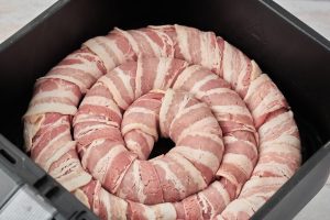 rå medister med bacon i airfryer kurven.