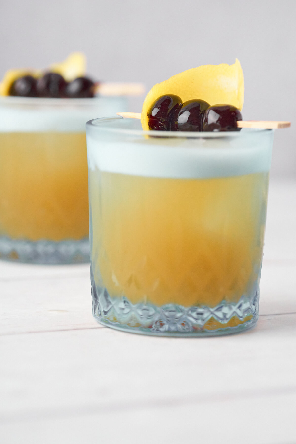 glas med klassisk amaretto sour med citron og kirsebær på toppen