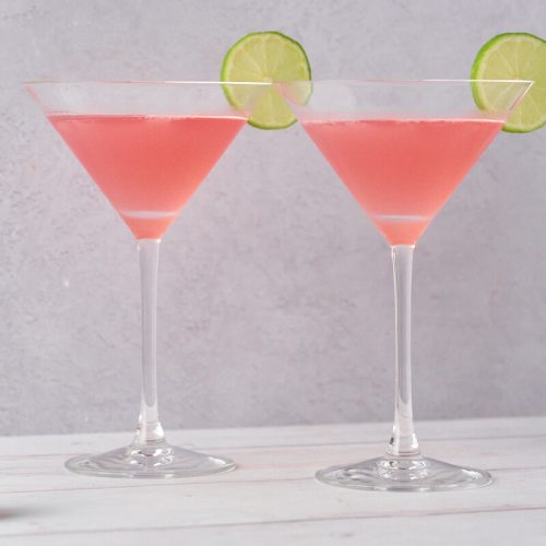 to glas med cosmopolitan med limeskiver og en cocktail shaker