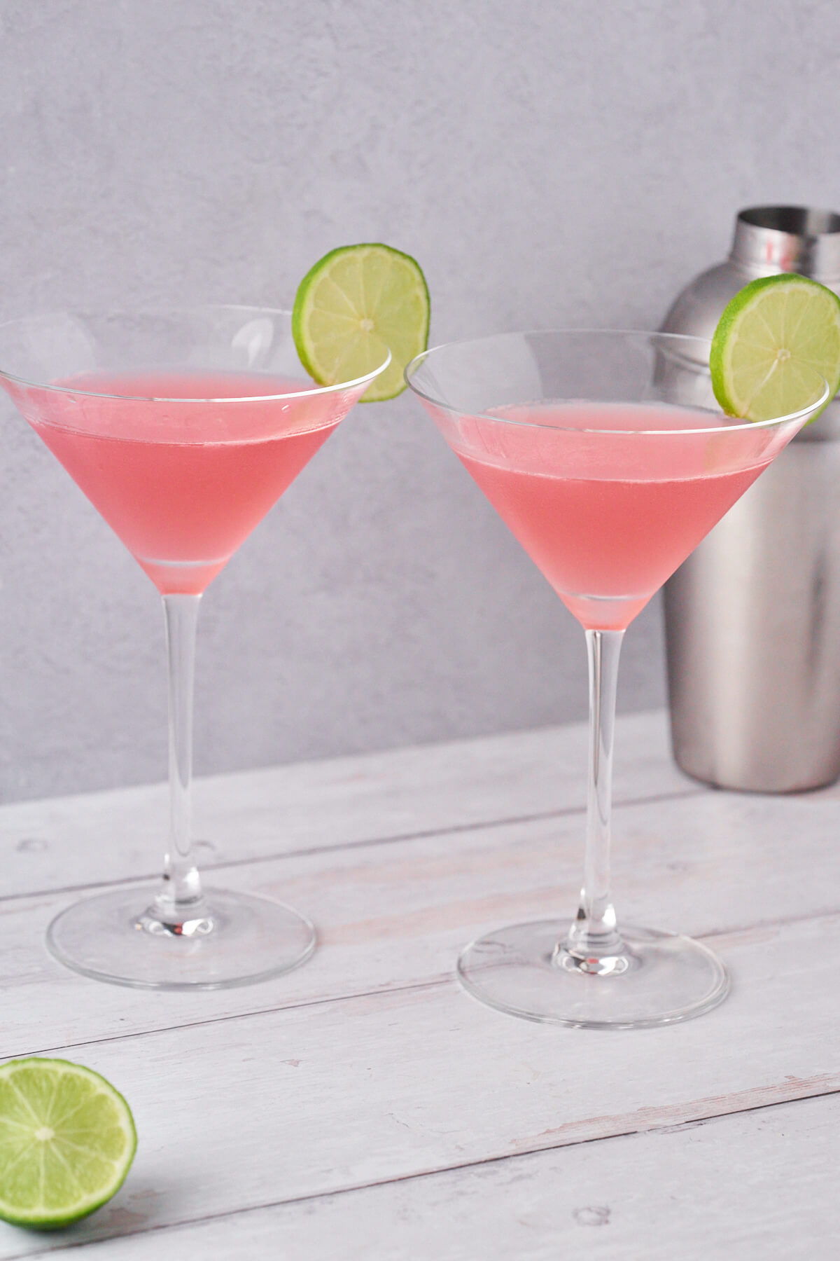 martiniglas med cosmopolitan med limeskiver og cocktailshaker