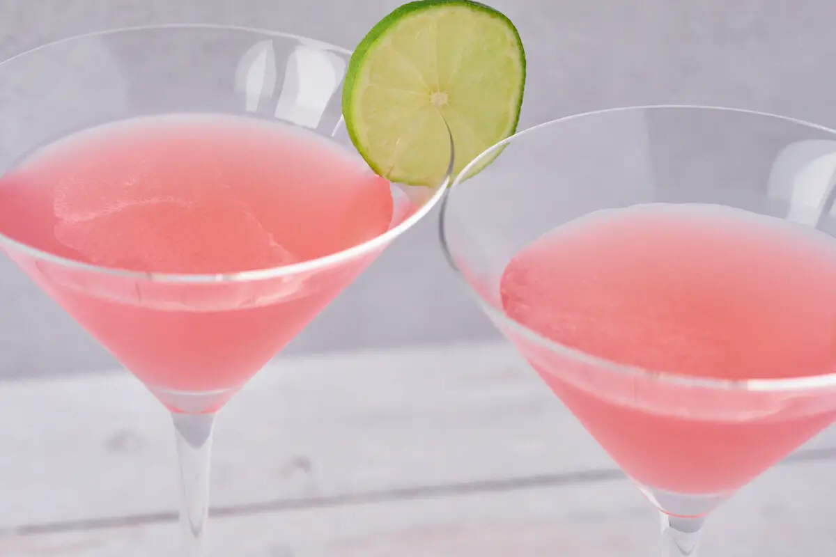 lyserøde cosmopolitan drinks med limeskive i martiniglas