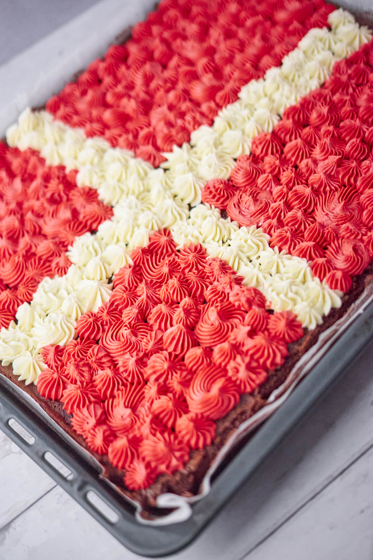 brandepande med chokoladekage med farvet smørcreme, der er sprøjtet ud i små dutter som et Dansk flag til fødselsdag.