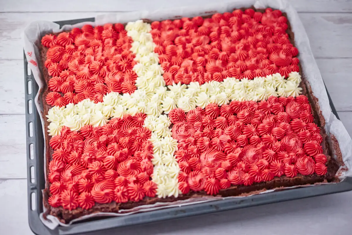chokoladekage med smørcreme i en bradepande, smørcremen er rød og hvid og sprøjtet ud med en stjernetylle som et Dansk flag.