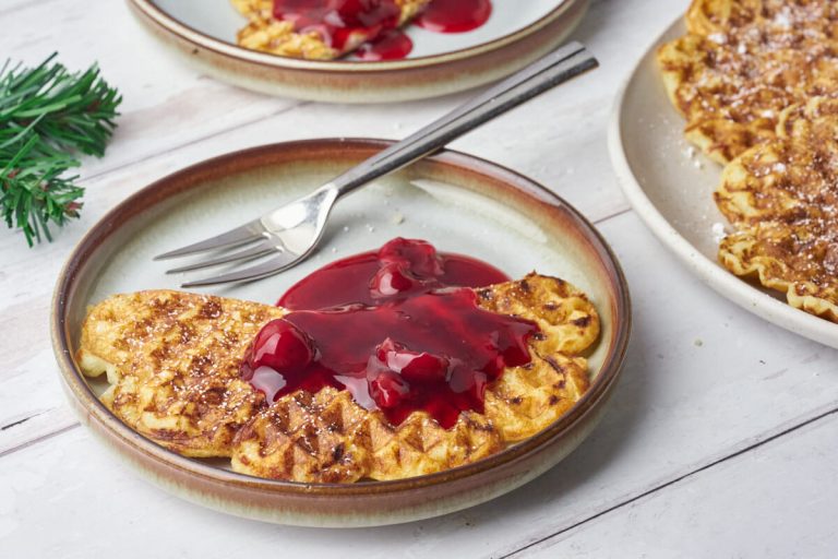 risalamande vafler på tallerkener serveret med kirsebærsovs og flormelis.