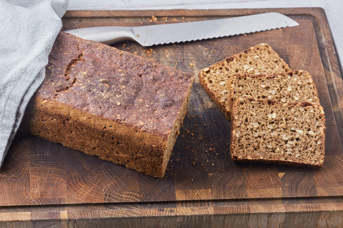 skærebræt med rugbrød der er skåret i skiver med brødkniv.