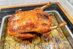 Andesteg der lige er kommet ud af ovnen på et fad med grøntsager i bunden og skyen der bliver til sovs.